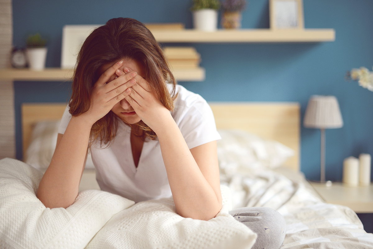 Eine Frau sitzt traurig in ihrem Bett