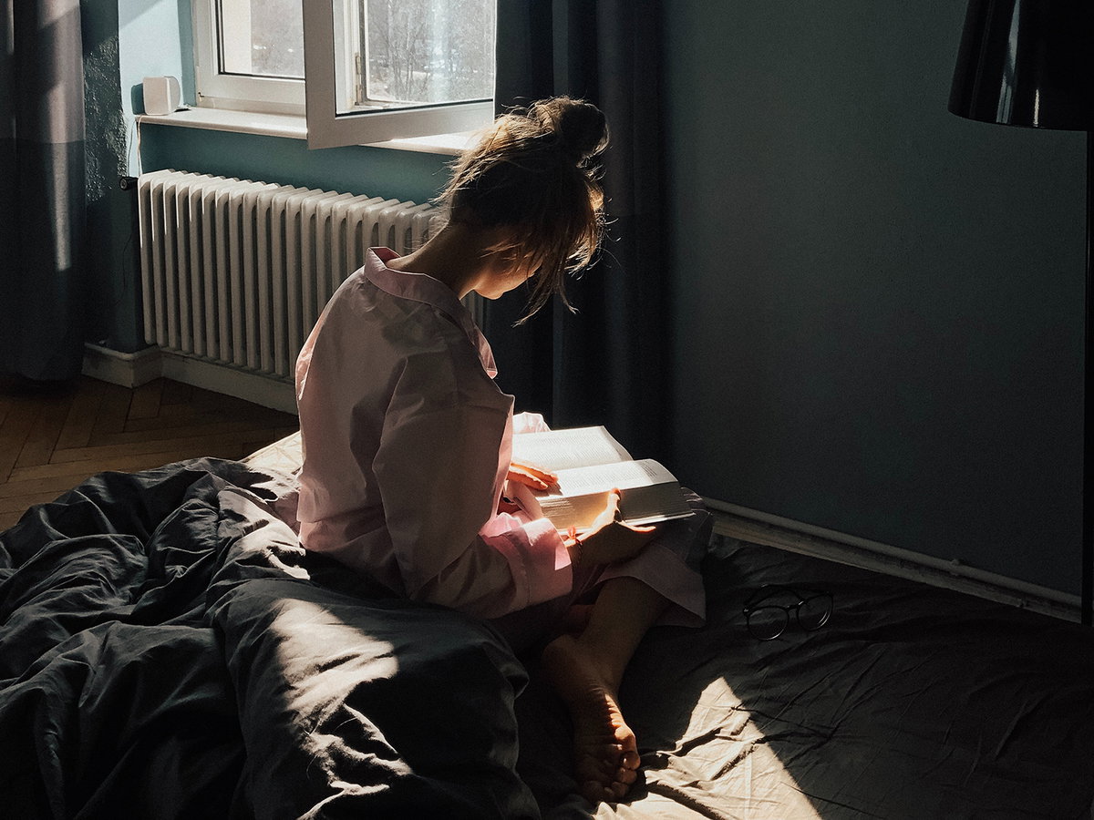 Frau liest Buch auf Bett