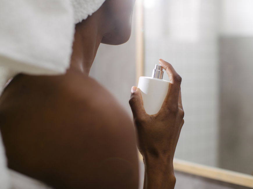 Frau sprüht sich mit Parfum ein
