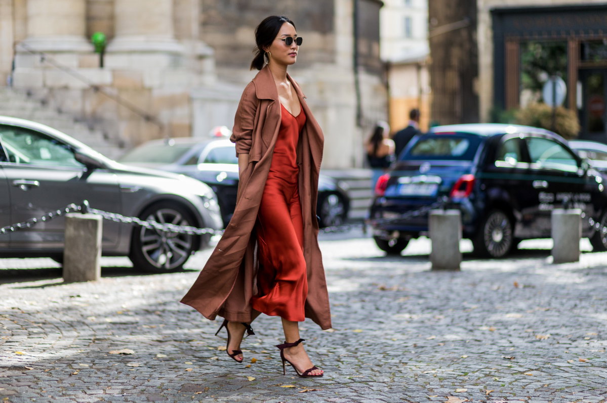 Frau in einem rostroten Slip Dress mit einem Trenchcoat