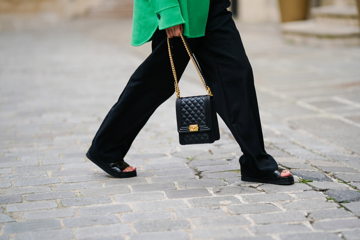 Frau trägt schwarze Sandalen schwarze Tasche und Hose Streetstyle