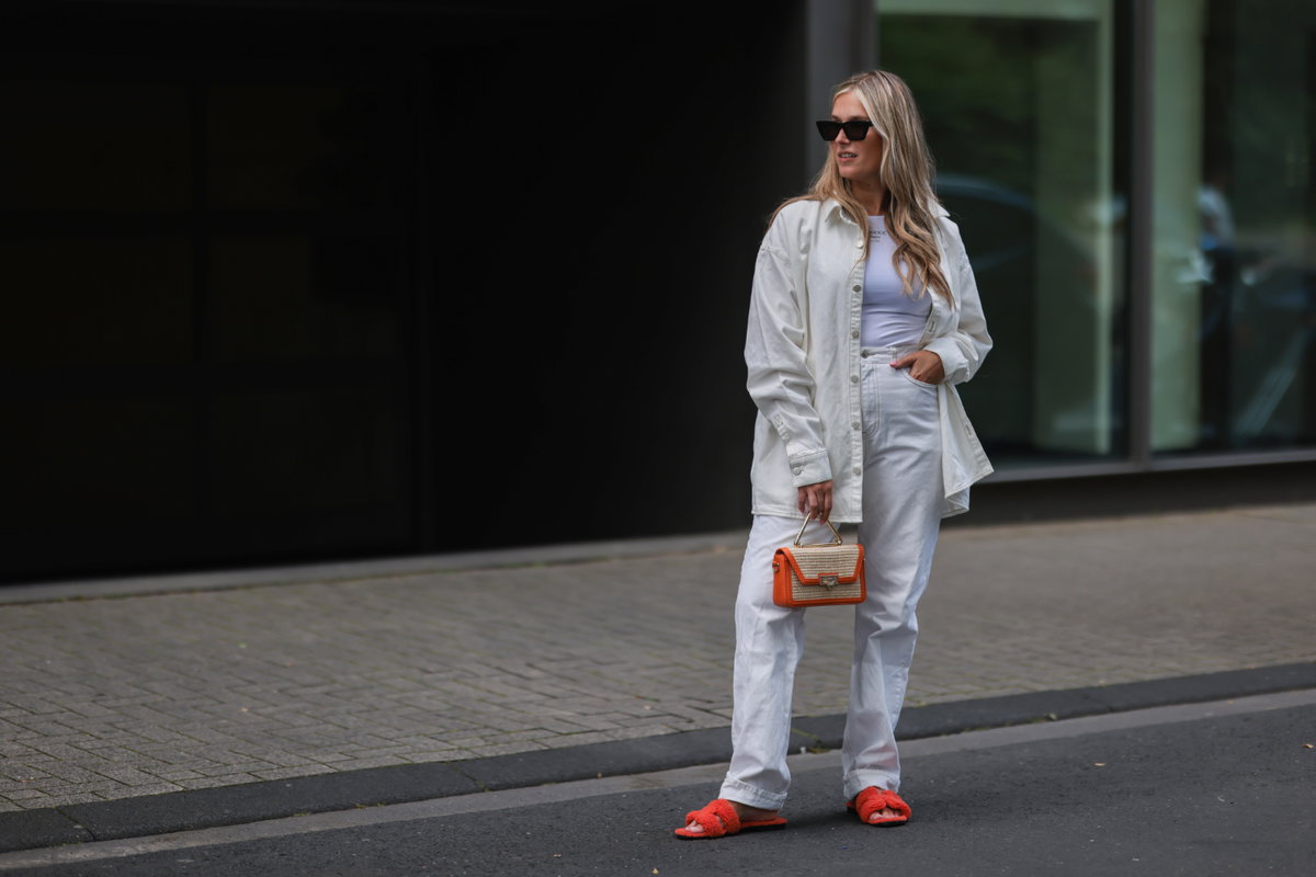 Frau trägt weißes Outfit orangene Details Sandalen Streetstyle