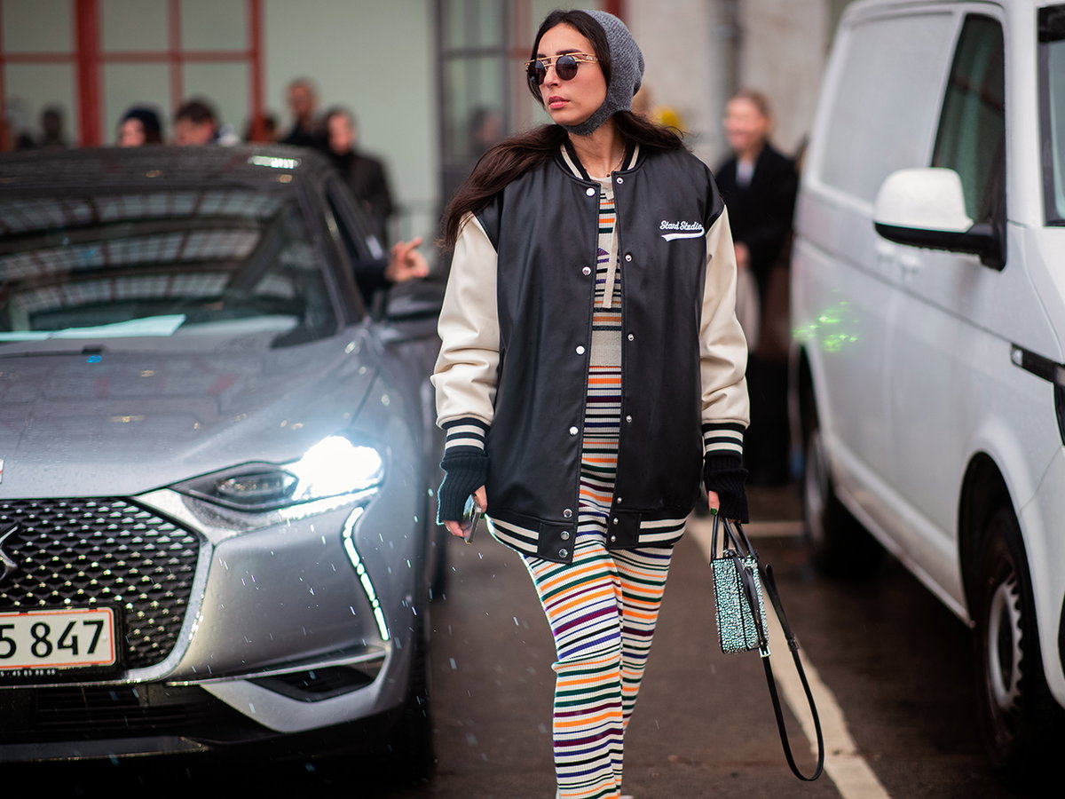 Stylische Frau in einer Collegejacke mit Maxikleid