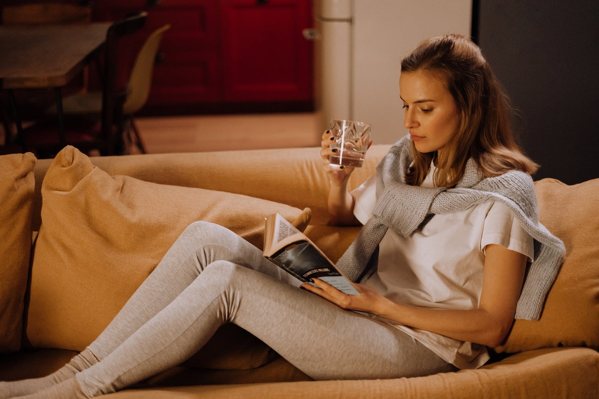 Frau liest Buch auf dem Sofa