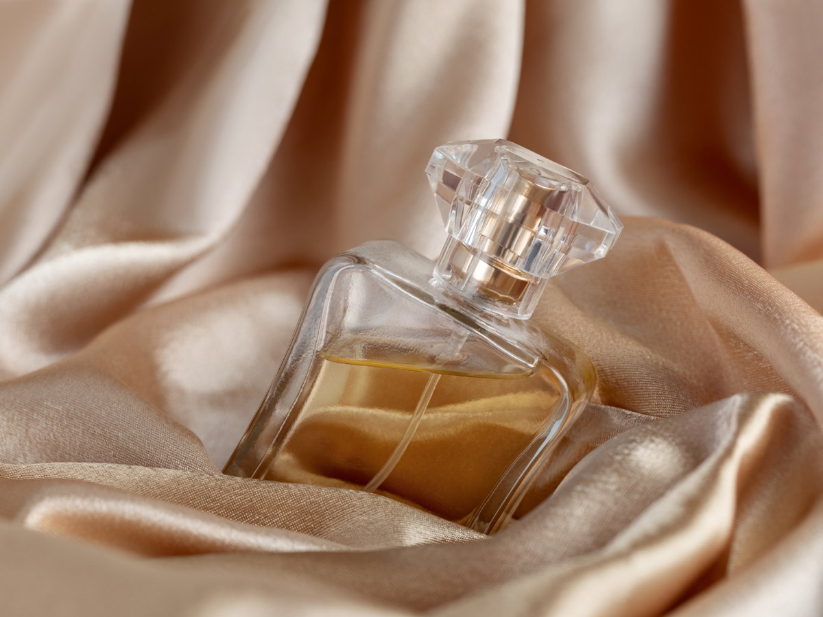Glasflasche Parfüm auf goldene Seide Hintergrund