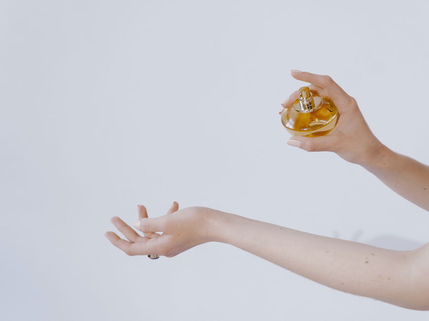 Frau sprüht sich mit Parfum ein