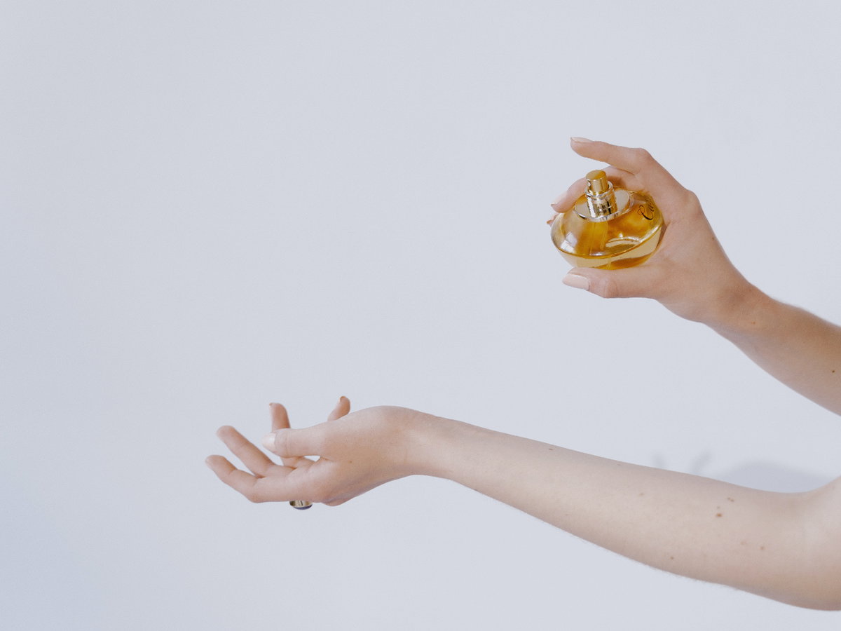 Frau sprüht sich mit Parfum ein