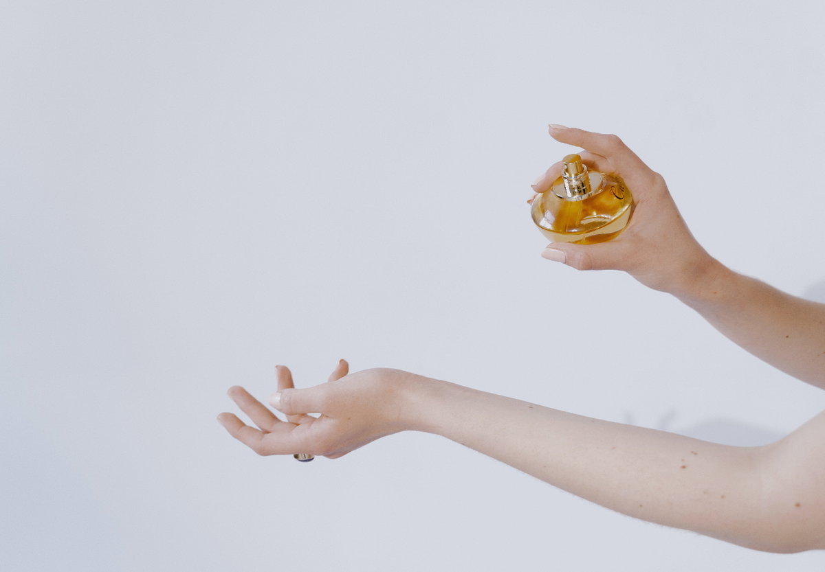 Frau sprüht sich mit Parfum ein
