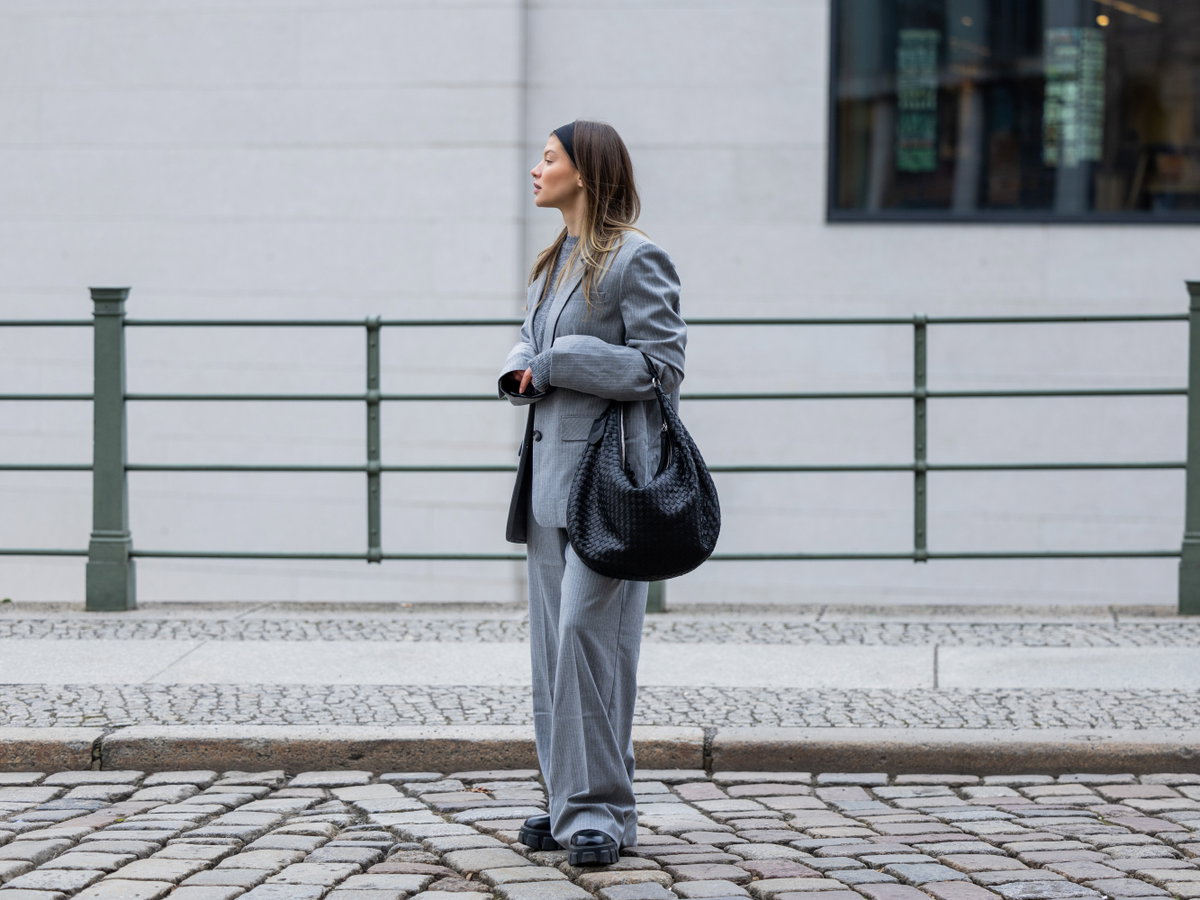 Sophia Geiss trägt grauen Blazer und graue Hose Haarband Schwarze Boots
