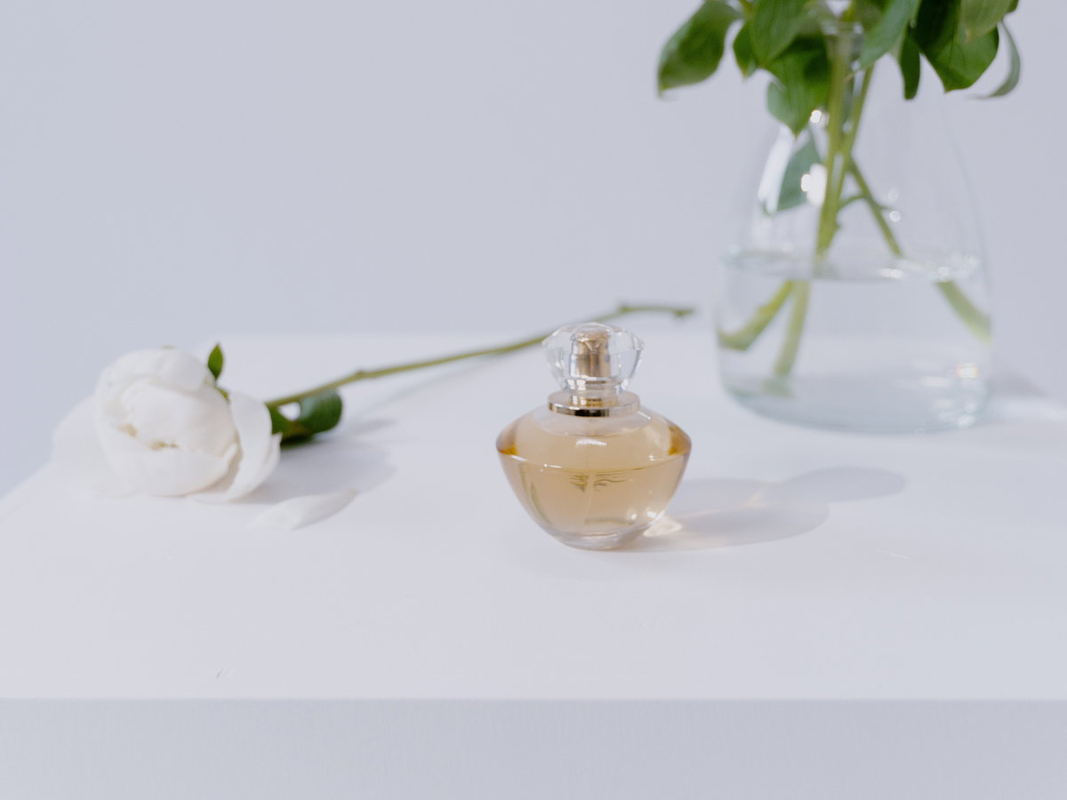 Parfum Flakon vor Vase mit Blumen