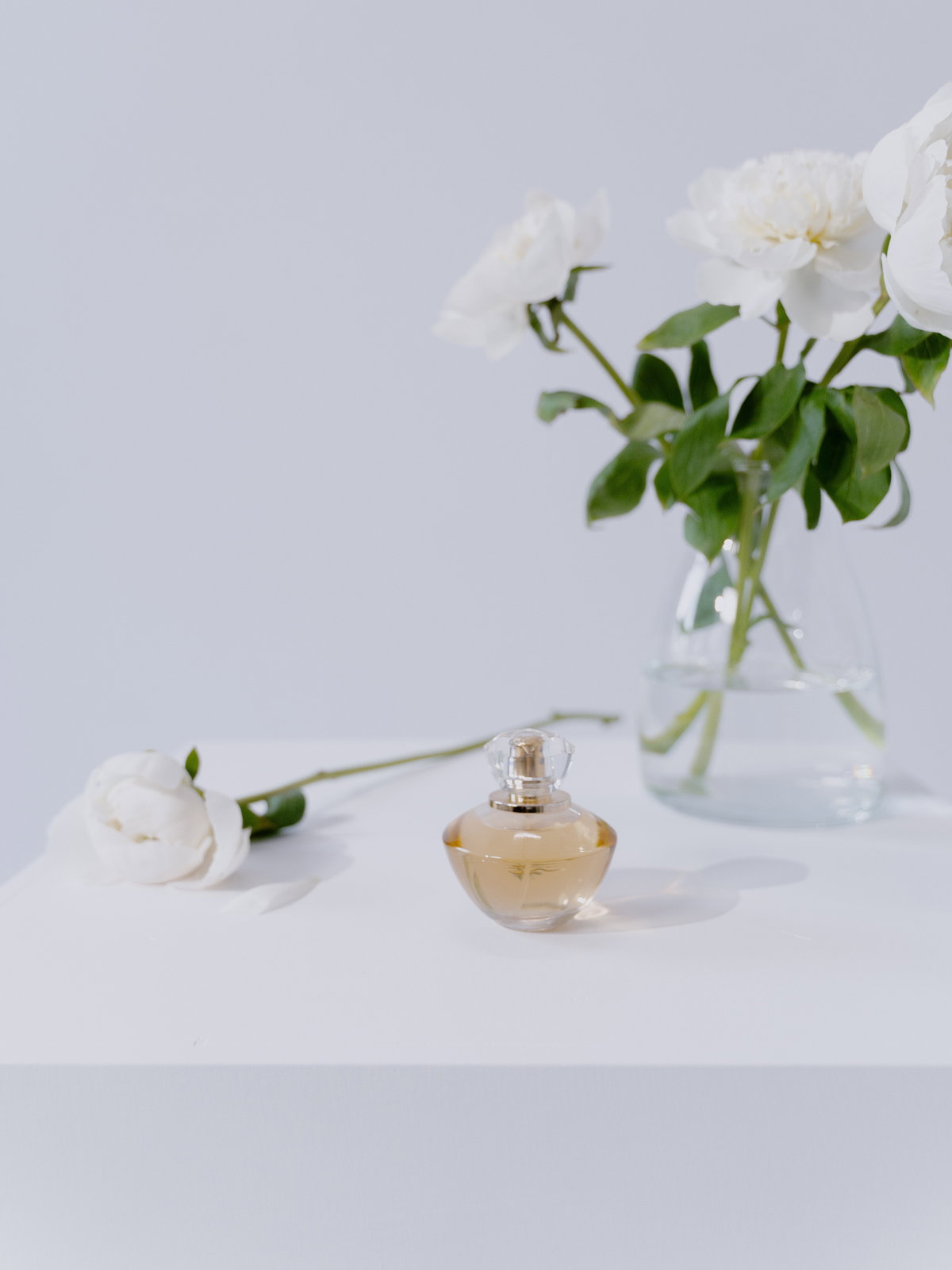 Parfum Flakon vor Vase mit Blumen