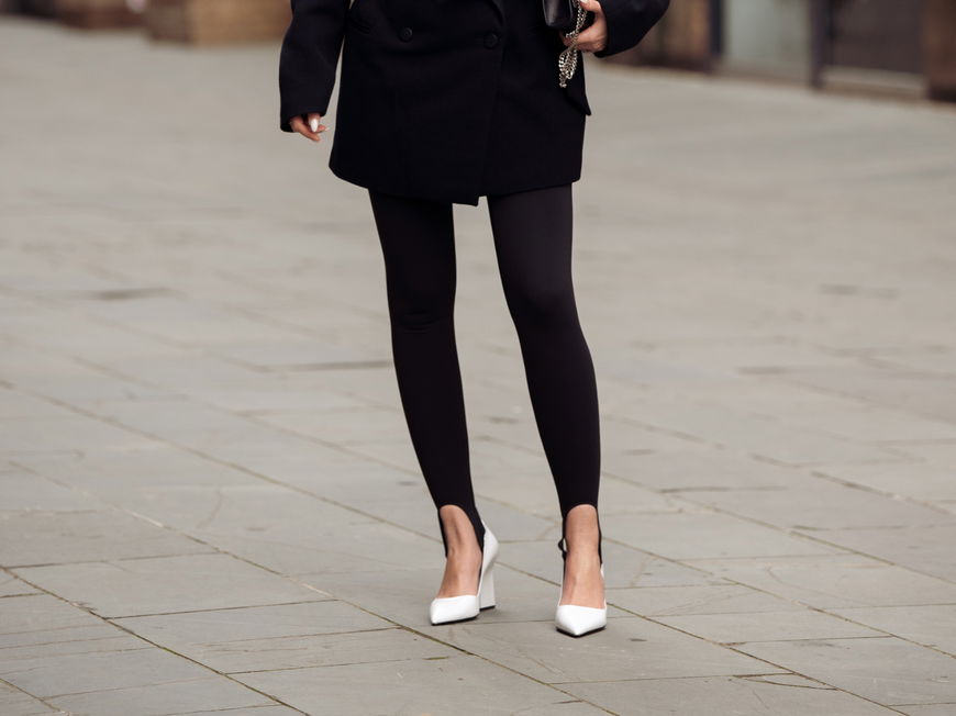 Erna Leon trägt schwarze Leggings mit Steg weiße Heels und schwarzen Blazer