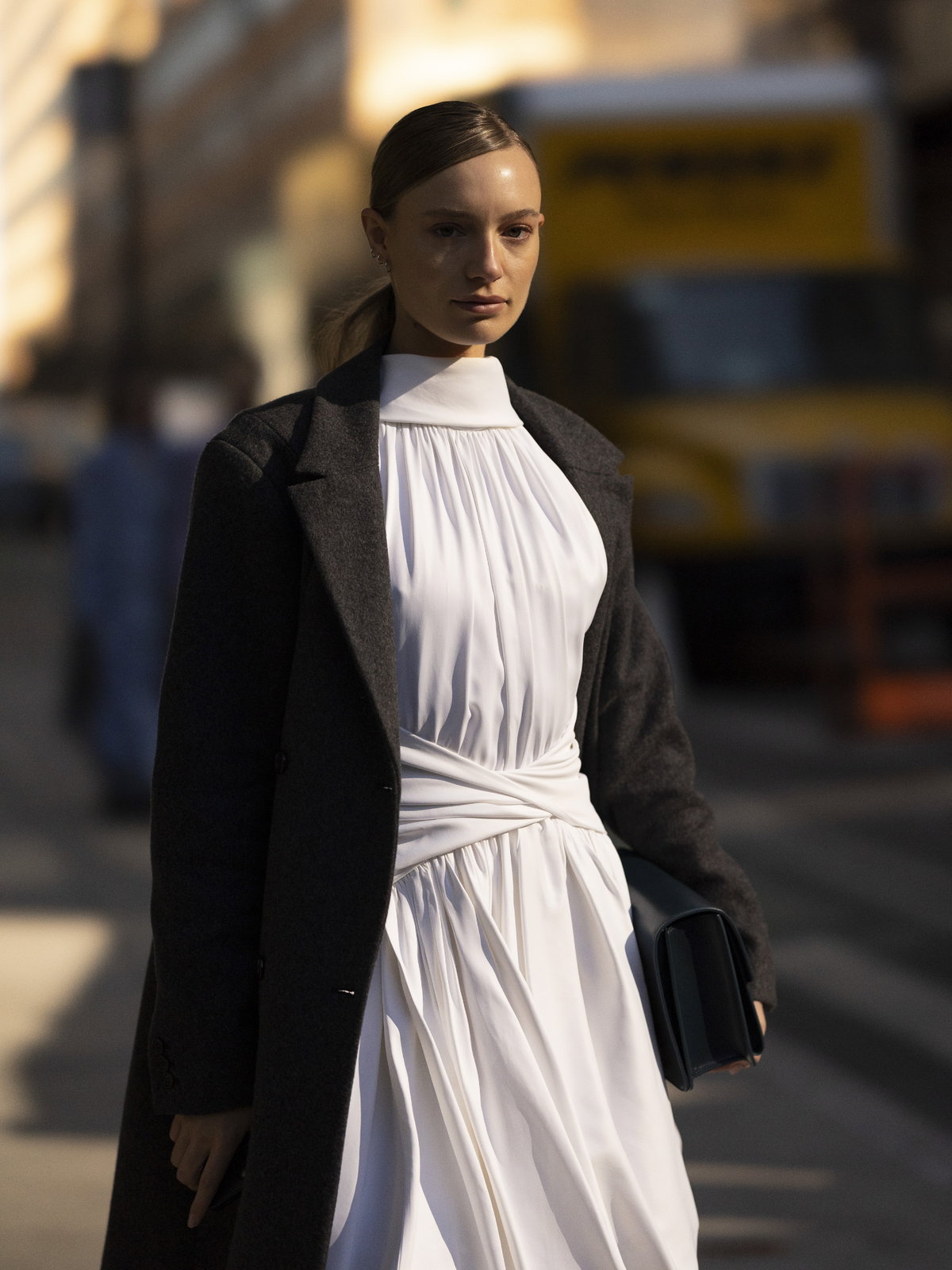Frau trägt weißes Kleid und schwarzen Mantel New York Fashion Week