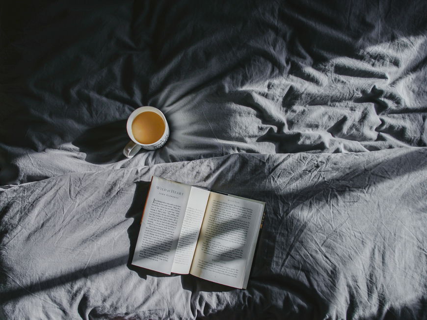 Bett mit Tasse Kaffee Bettdecke und Buch