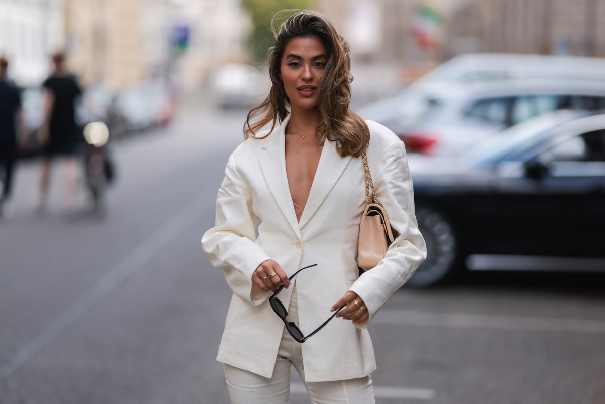 Frau trägt einen hellen Leinen-Blazer mit beiger Chanel-Tasche