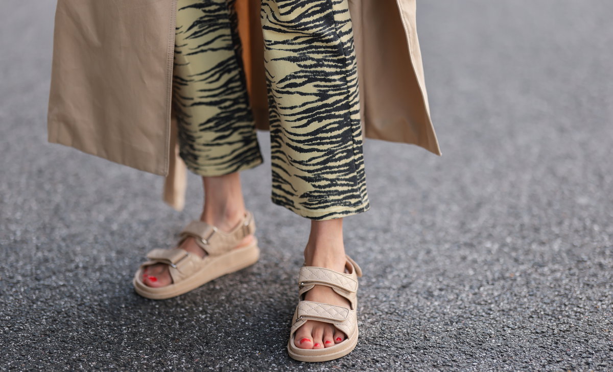 Frau trägt beige Sandalen und eine gemusterte Hose