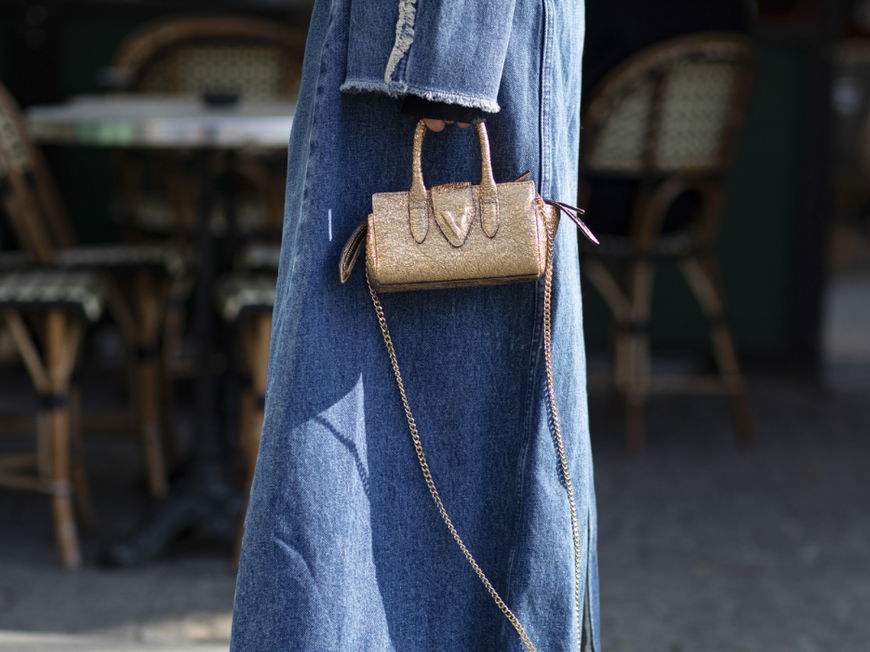 Frau trägt Jeansmantel Jeansschuhe Streetstyle goldene Tasche