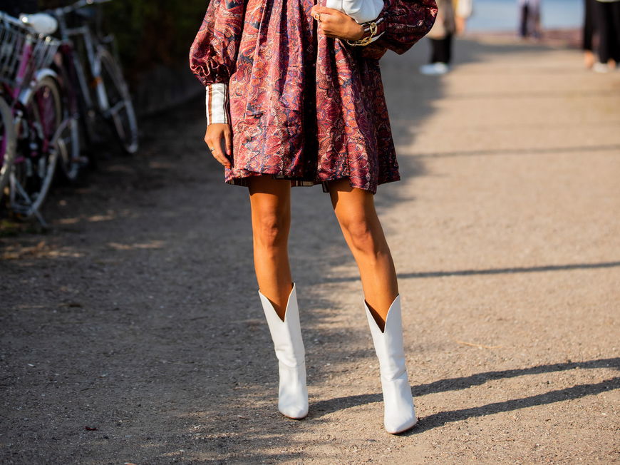 Eine Frau trägt ein Kleid und weiße Cowboystiefel