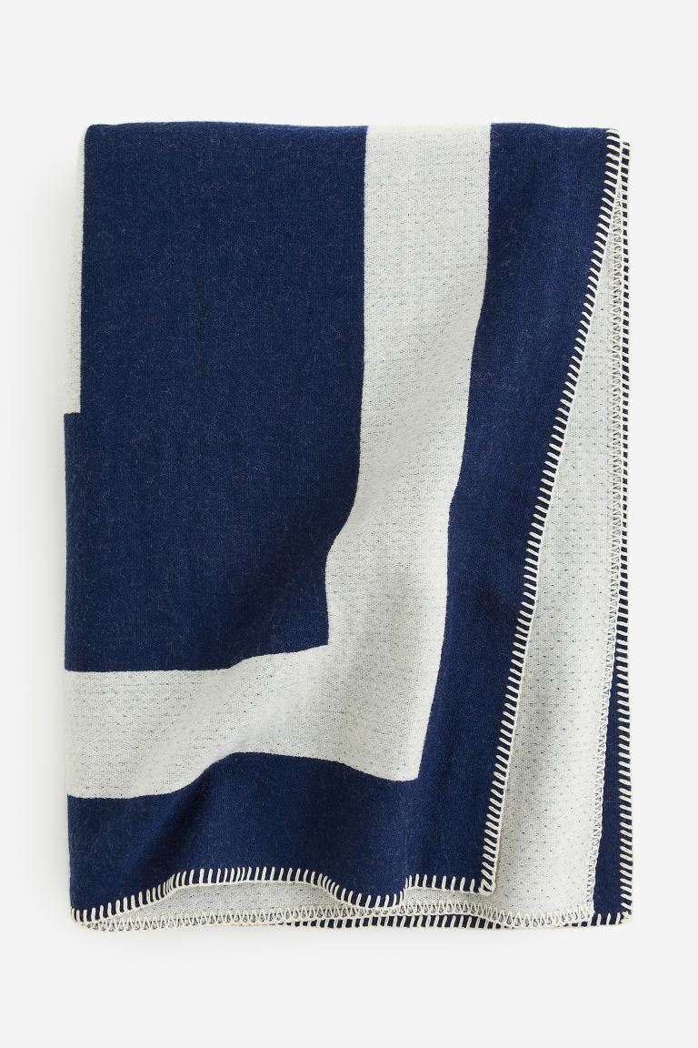 Jacquard-Decke aus Merinowolle in Blau-Weiß von H&M Home, ca. 90 Euro