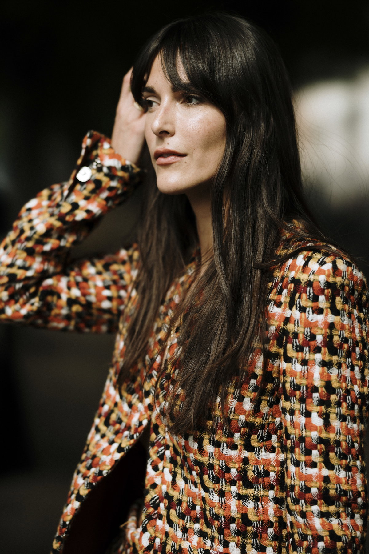 Paris Fashion Week Streetstyle Frau trägt Jacke mit Karomuster lange braune Haare und Pony