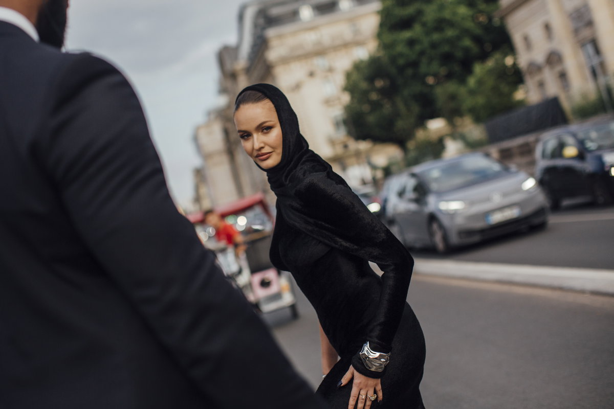 Paris Fashion Week Streetstyle Frau trägt schwarzes Kleid mit Kapuze