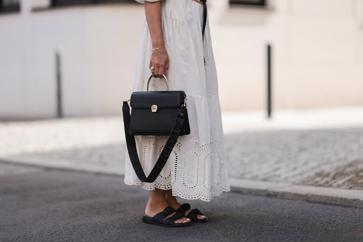 Eine Frau trägt ein weißes Kleid und schwarze Sandalen