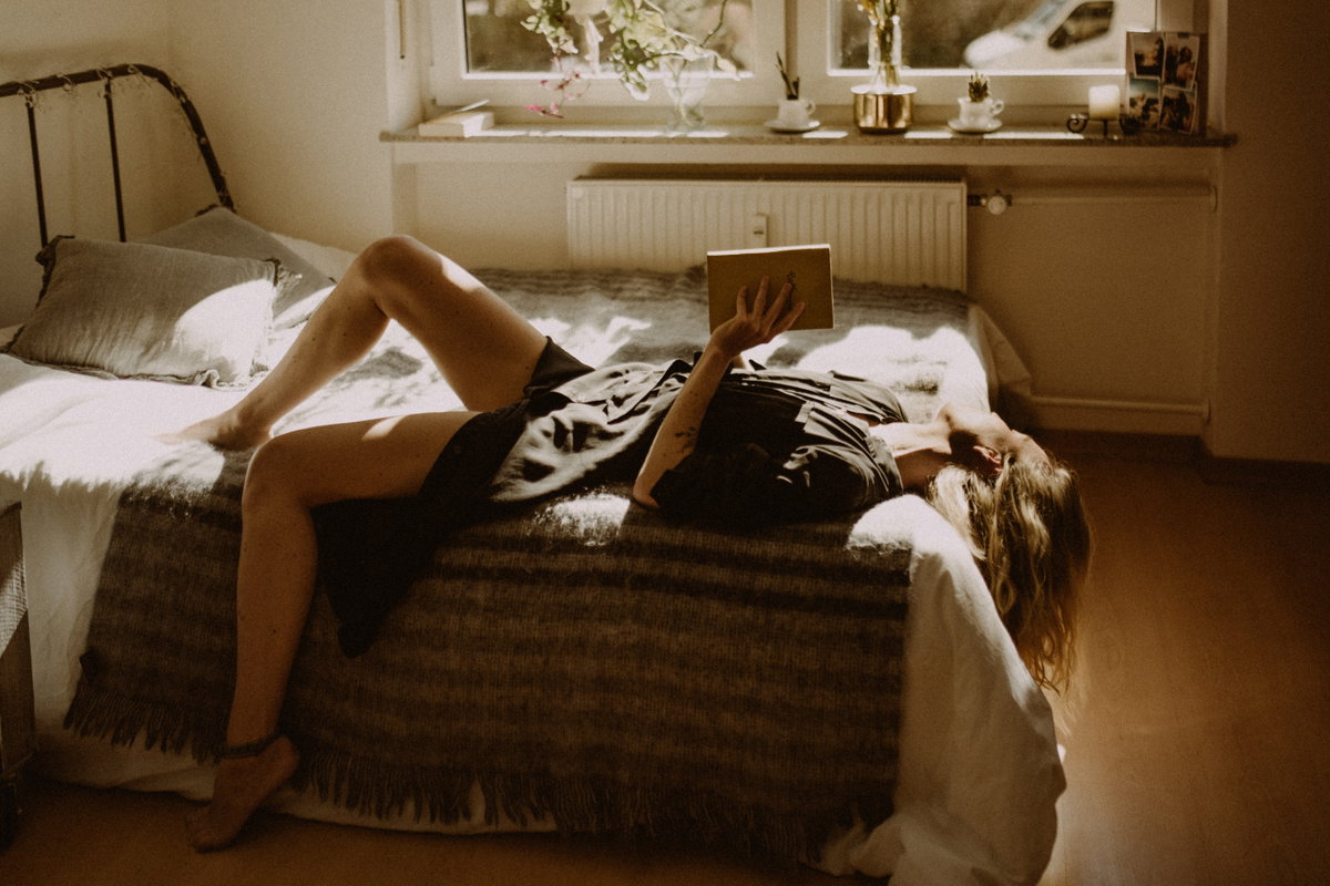 Frau auf dem Bett mit einem Buch in der Hand