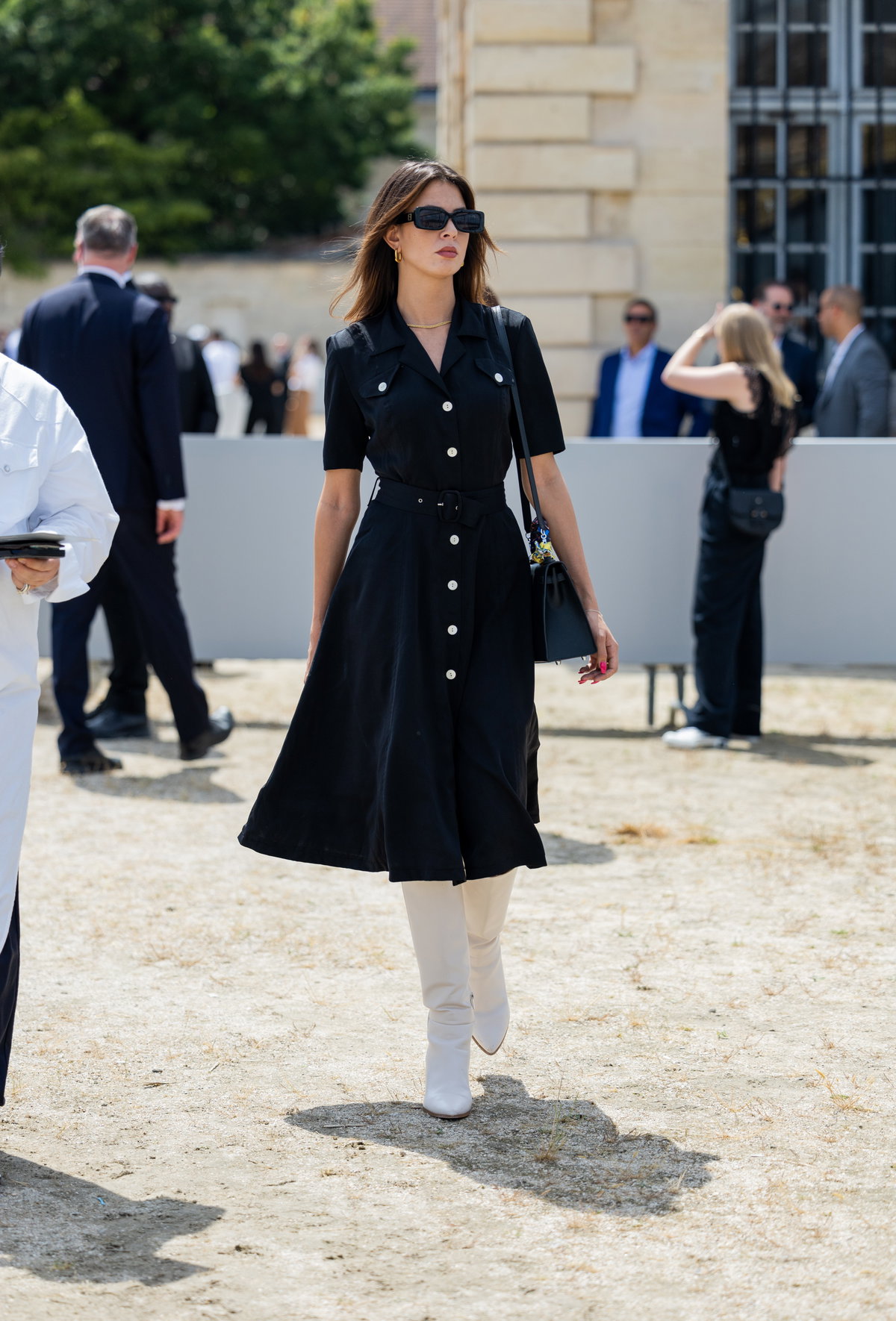 Frau in Paris trägt schwarzes Kleid mit Stiefeln