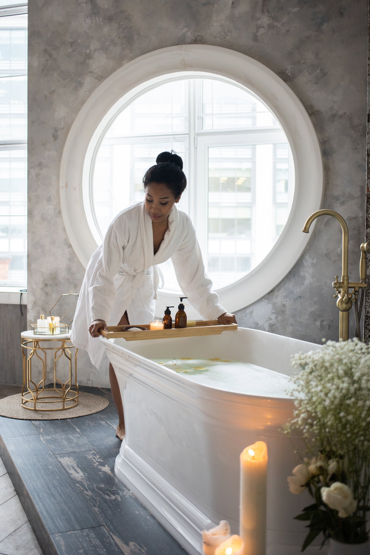 Frau im Bademantel stellt ein Tablett auf die Badewanne