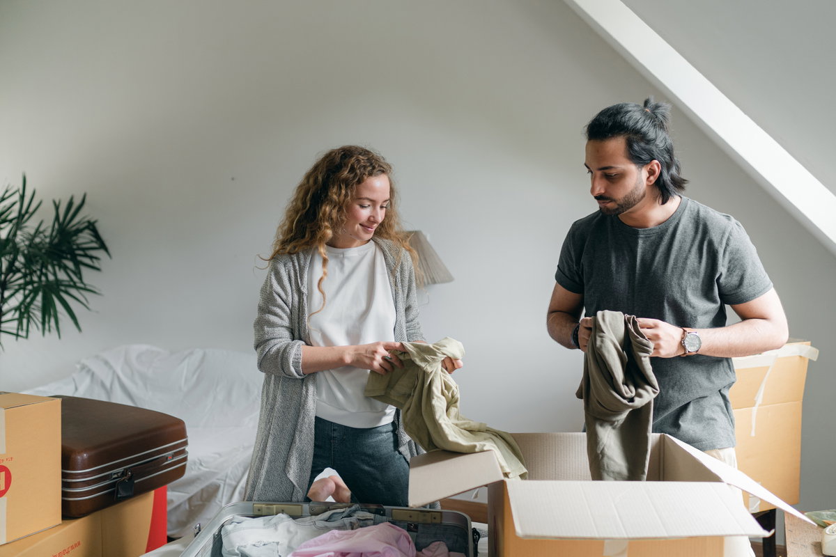 Paar steht vor einer Kiste und sortiert Kleidung aus