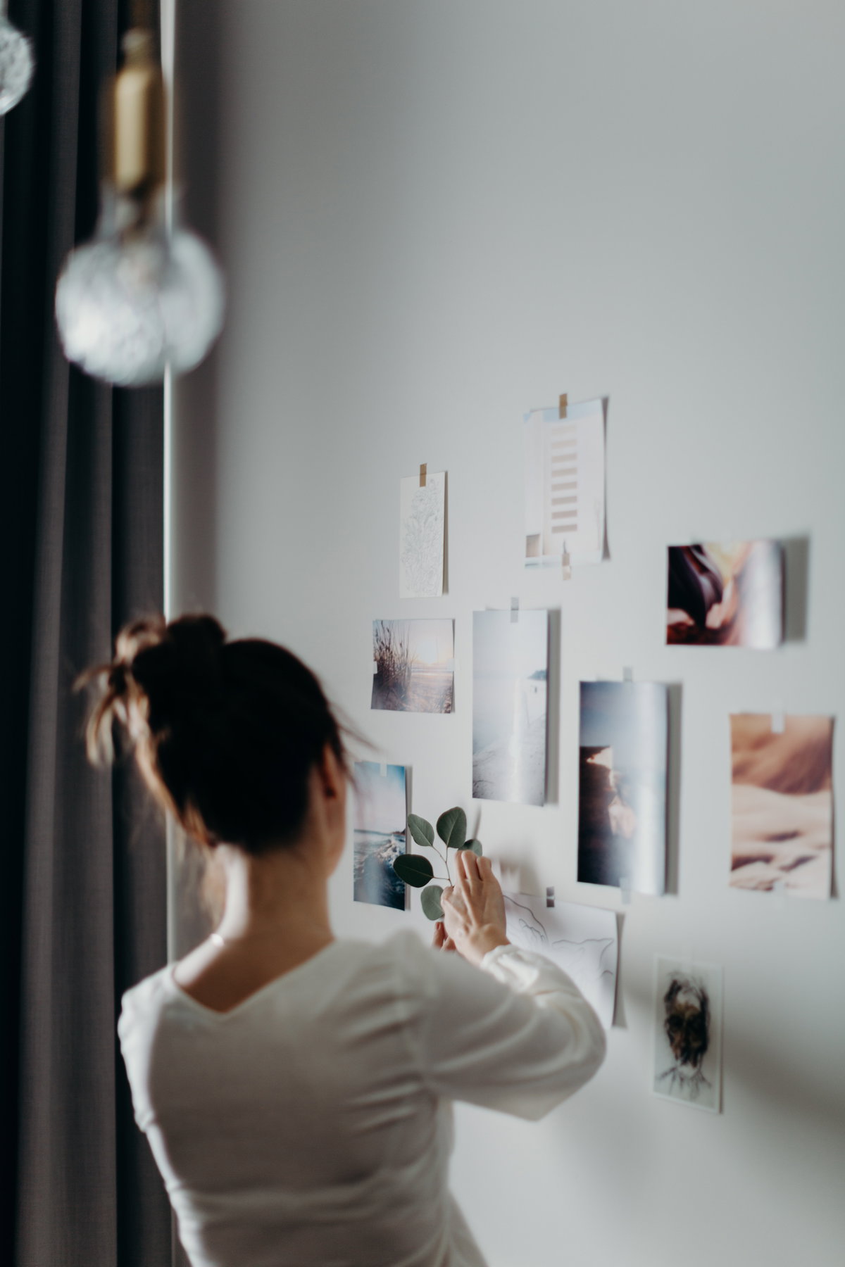 Frau dekoriert eine Wand mit Fotos