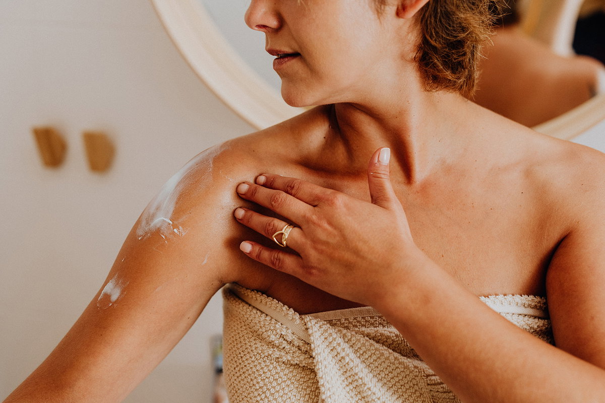 Frau cremt sich mit Bodylotion ein