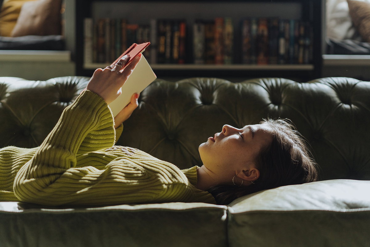 Frau liest Buch auf dem Sofa