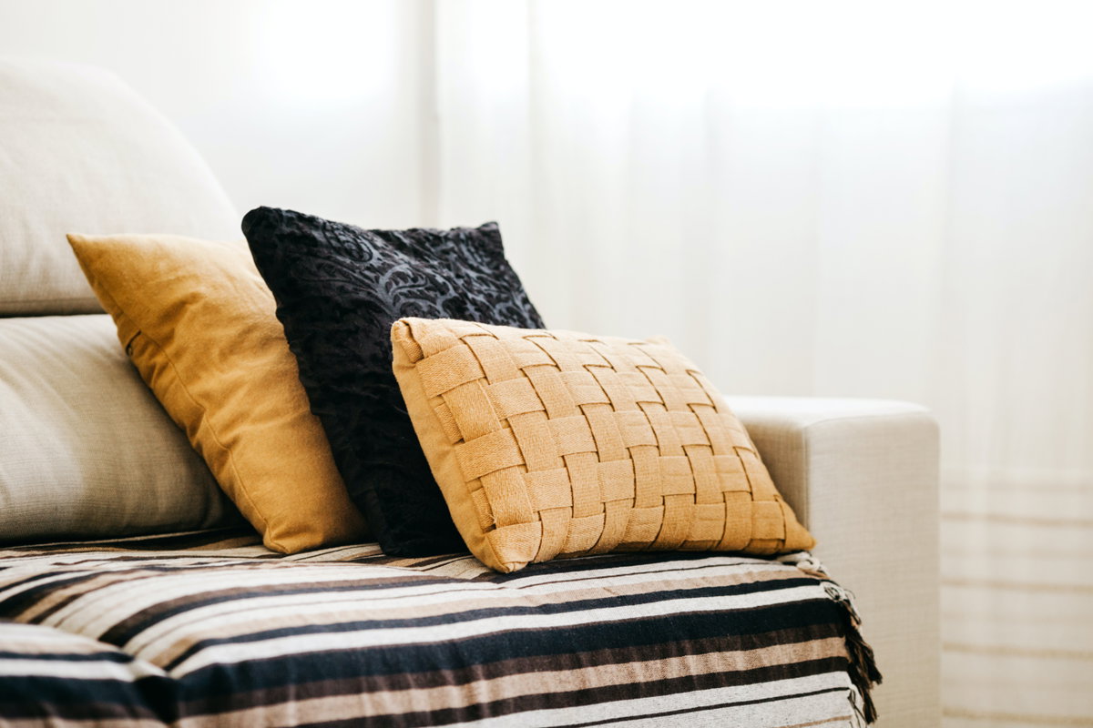 Schwarze und gelbe Kissen liegen auf einem beigefarbenen Sofa
