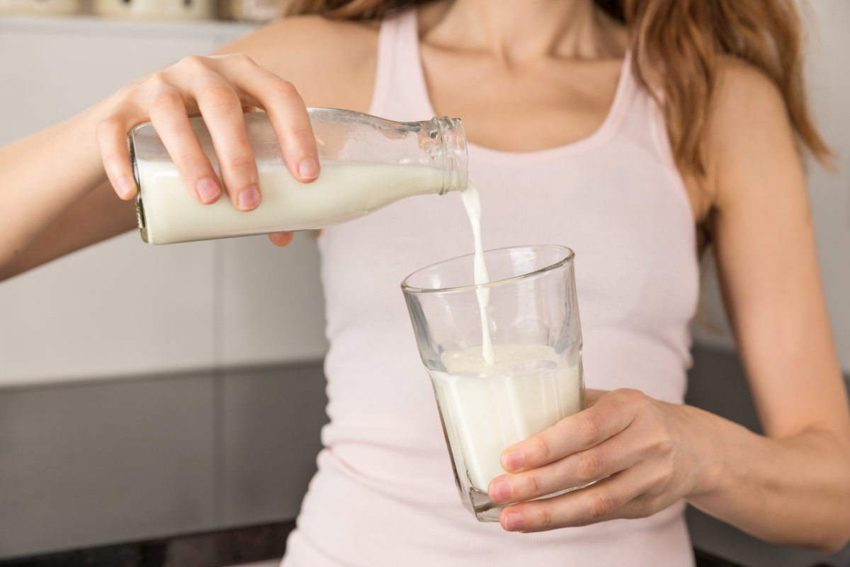 Frau gießt Milch in ein Glas