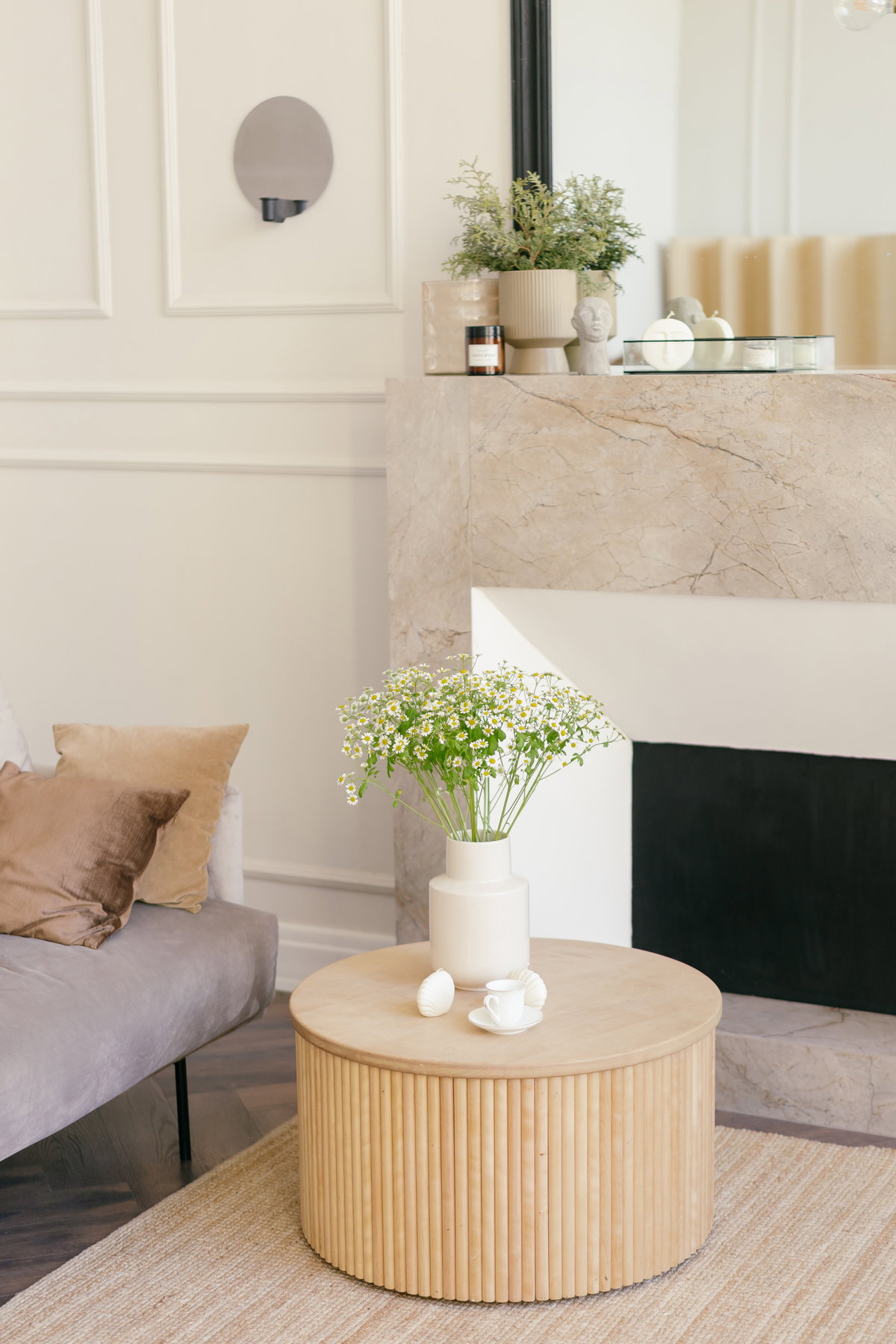 Weiße Vase steht auf einem runden Couchtisch aus Holz im Wohnzimmer