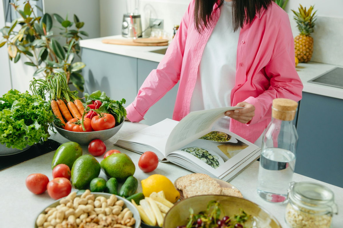 Frau kocht vegan mit Kochbuch