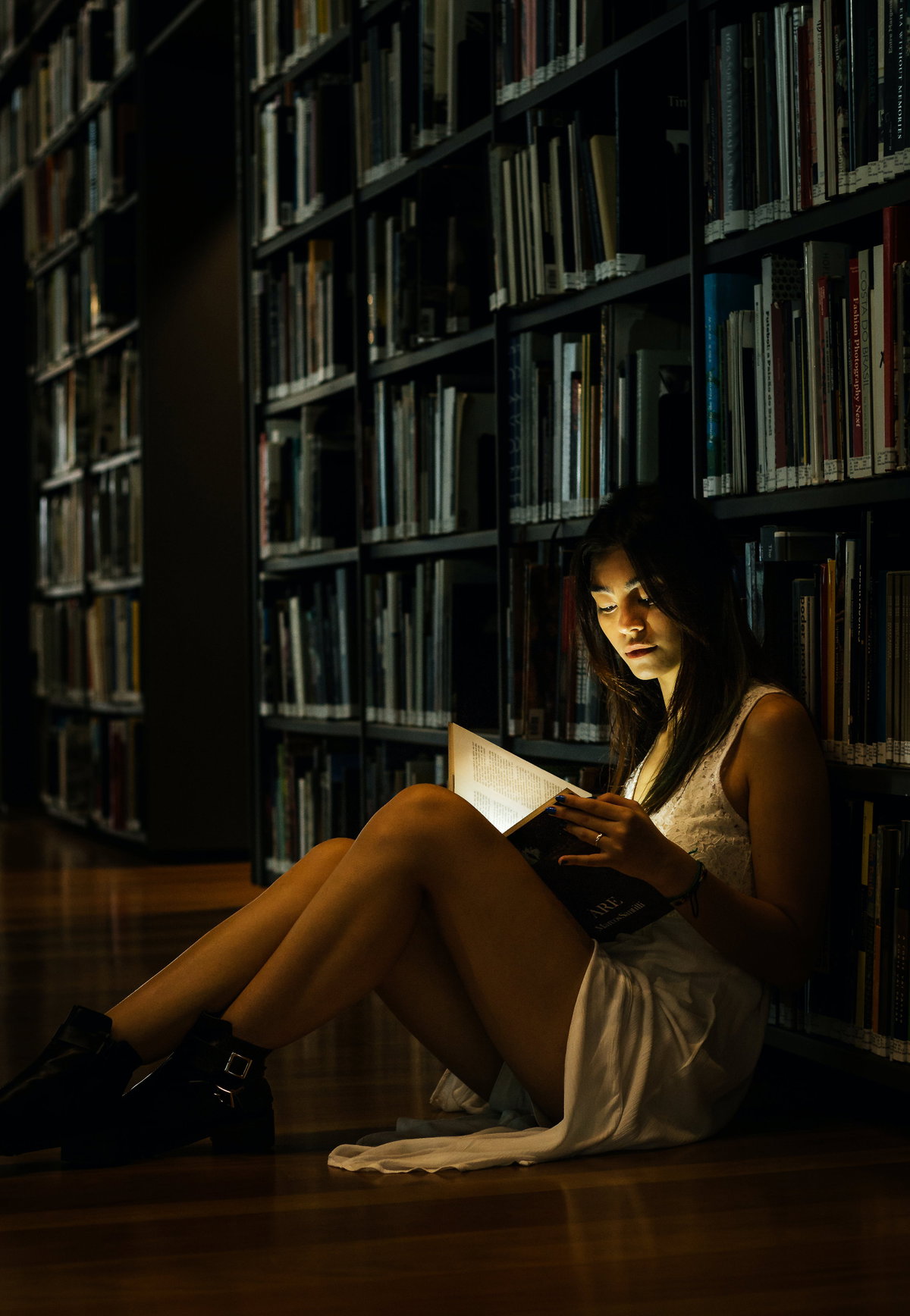 Frau im Kleid liest ein Buch in einer Bibliothek