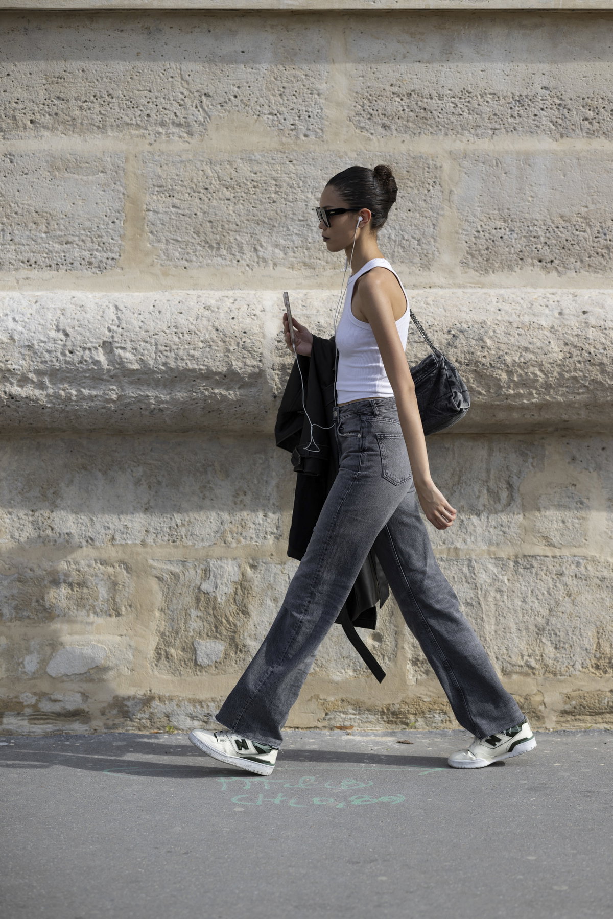 Frau trägt auf Paris Fashion Week Jeans in Grau mit Sneakern und Top Streetstyle