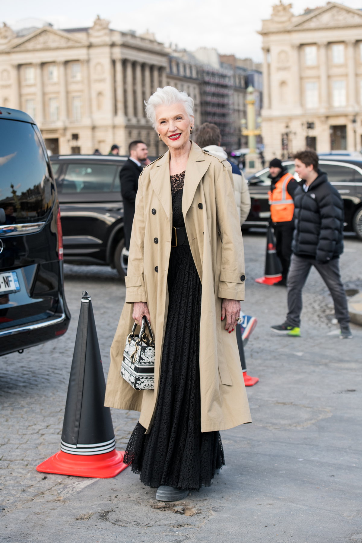Maye Musk auf Dior Show 2023 mit beigem Trenchcoat und schwarzem Kleid Streetstyle lässige Kleidung für Frauen ab 60