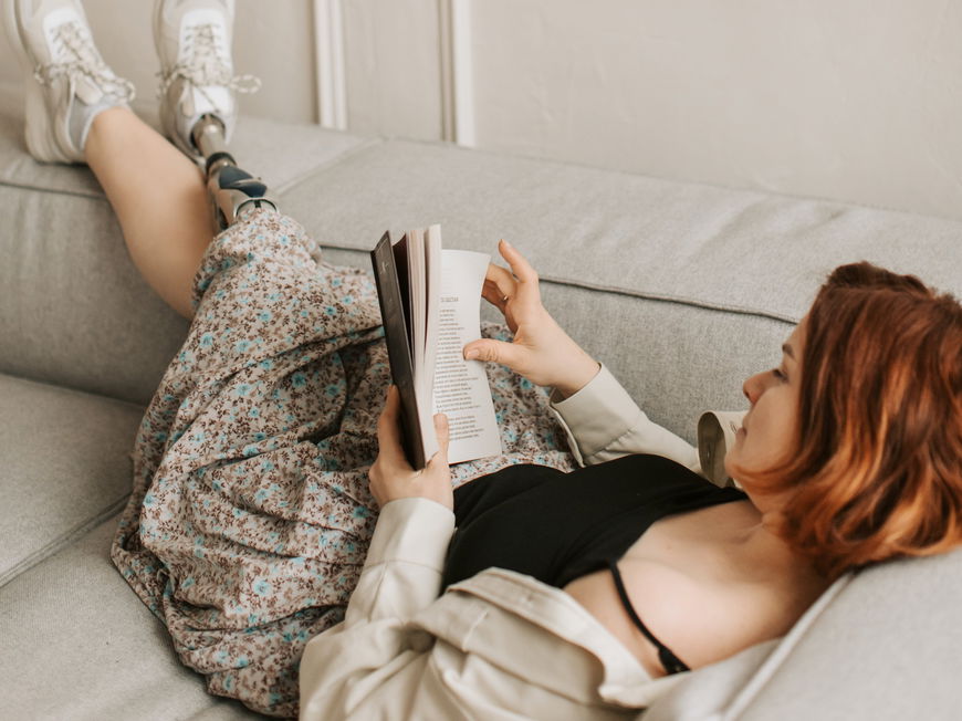 Frau liest ein Buch auf der Couch