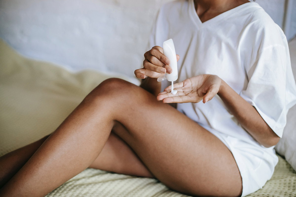 Frau cremt sich mit Bodylotion ein