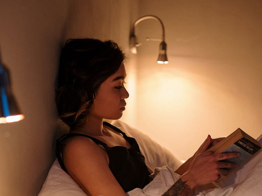 Frau liest Buch im Bett