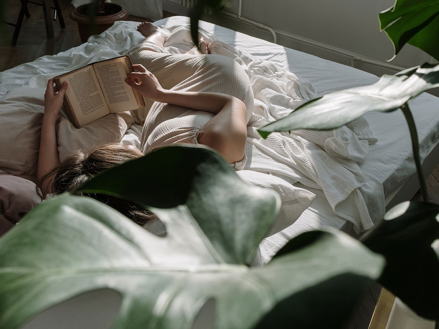 Frau liest Buch im Bett