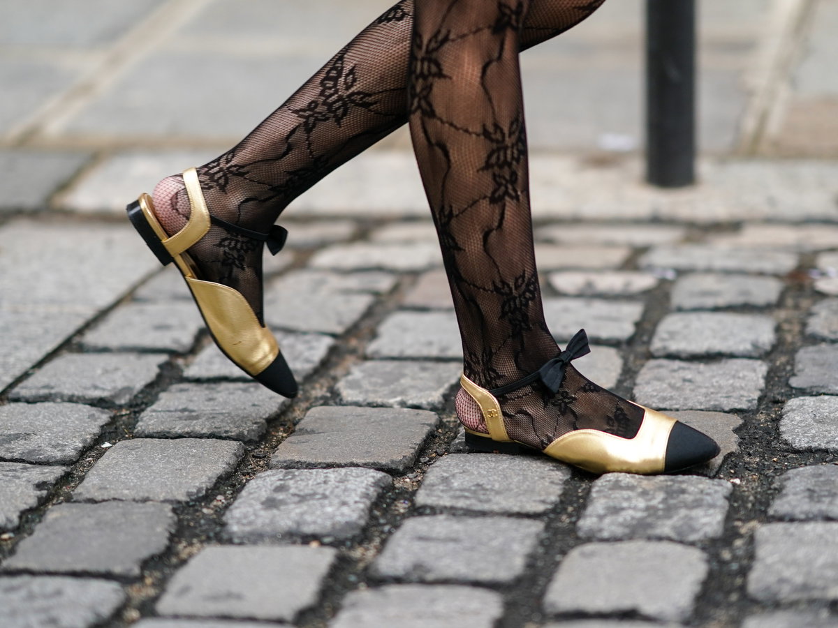 Frau trägt Ballerinas in  Gold und Schwarz