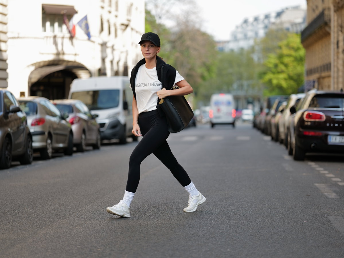 Diane Batoukina trägt schwarze Sport-Leggings weißes T-Shirt schwarze Cap und schwarze Tasche
