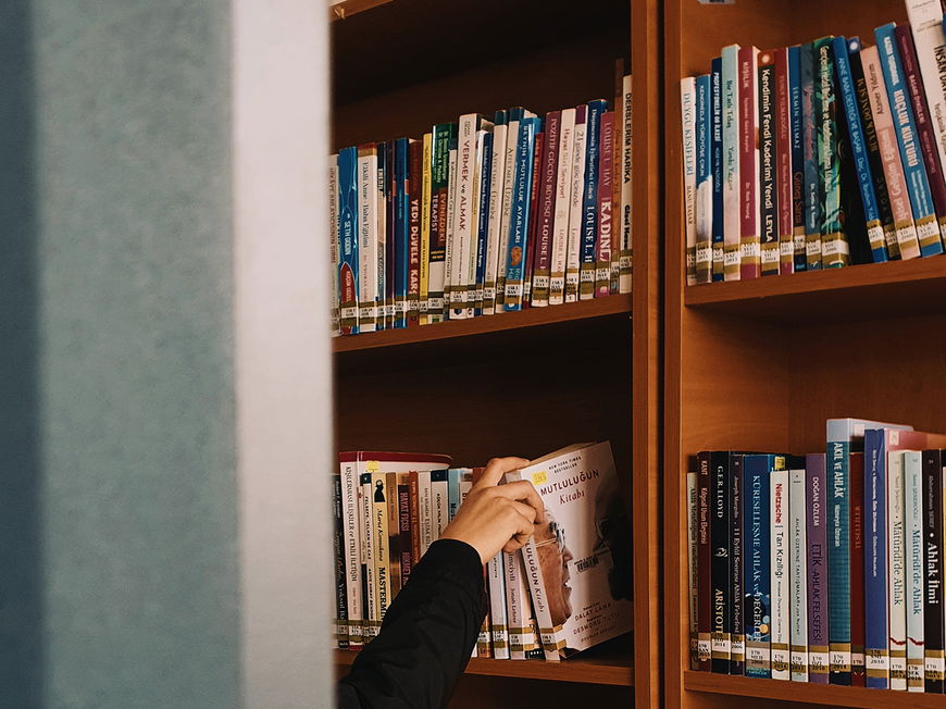 Frau greift in ein Bücherregal
