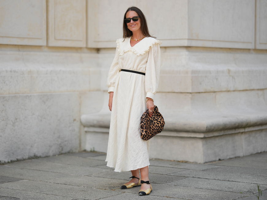 Frau in weißem Kleid und Leo-Tasche