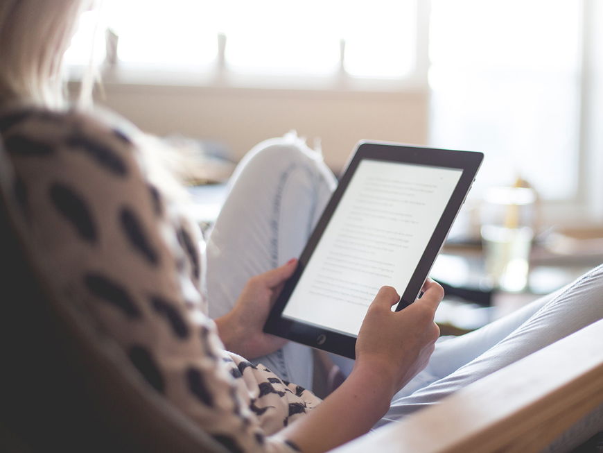Frau liest Buch auf dem Reader