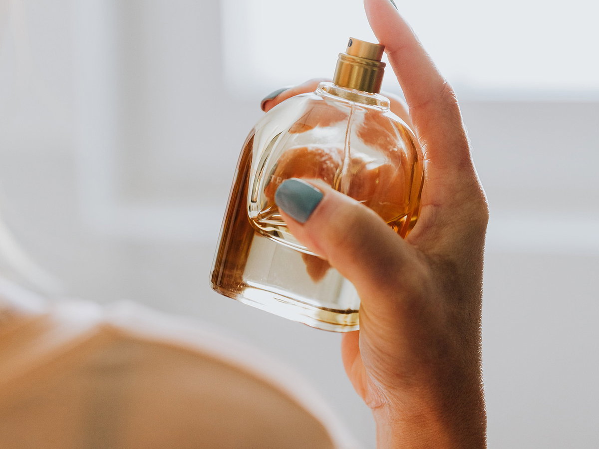 Frau sprüht Parfum auf